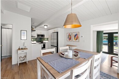 Unit A Dining room featuring french doors, beam ceiling, sink, and light hardwood / wood-style flooring