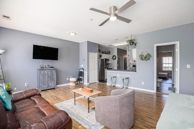 Living area with a ceiling fan, wood finished floors, and baseboards