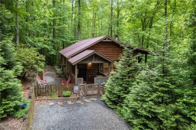 Rustic home with a gate, a porch, a wooded view, a