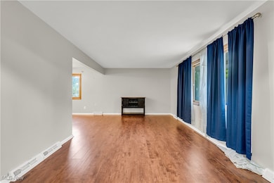 Unfurnished living room with wood finished floors and baseboards