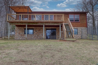 Rear view of property featuring stairway and stone siding