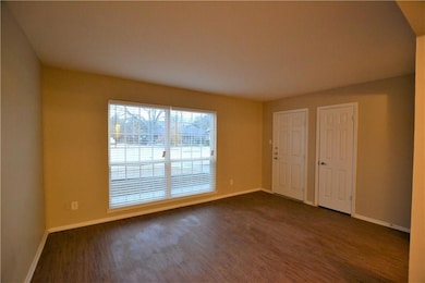 Unfurnished room featuring baseboards and dark woo
