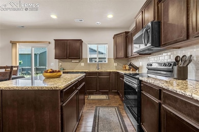 Kitchen featuring appliances with stainless steel finishes, dark wood-style flooring, plenty of natural light, backsplash, and recessed lighting