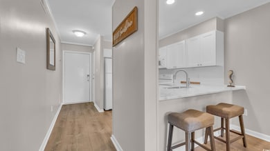 Hall with ornamental molding, a sink, light wood-s