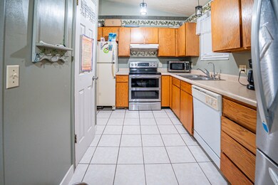 Kitchen with stainless steel appliances, lofted ceiling, light tile patterned floors, light countertops, and brown cabinets