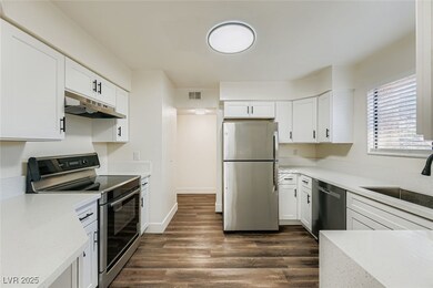 Kitchen featuring appliances with stainless steel finishes, light stone counters, white cabinetry, dark wood-style floors, and under cabinet range hood