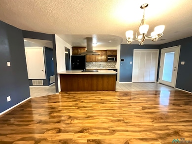 Kitchen featuring light countertops, hanging light fixtures, light wood-style floors, a textured ceiling, and a chandelier
