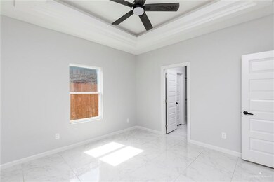 Unfurnished bedroom with light marble finish floors, a tray ceiling, baseboards, and a ceiling fan
