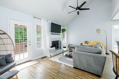 Living room featuring a ceiling fan, high vaulted ceiling, light wood-type flooring, and a fireplace with raised hearth