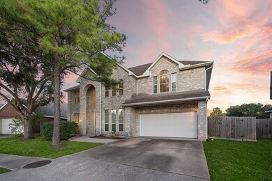 Stately two-story home with a grand arched entrance, large windows, and a double garage, set against a lush landscape.