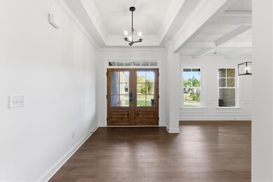 Entrance foyer with a chandelier, dark wood-type flooring, beam ceiling, french doors, and coffered ceiling