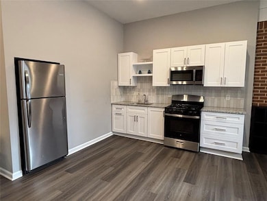 New Kitchen with gas stove, appliances with stainless steel finishes, open shelves, dark wood-style floors, tasteful backsplash, and white cabinets