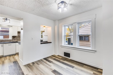 Unfurnished dining area with a textured ceiling and light wood-type flooring
