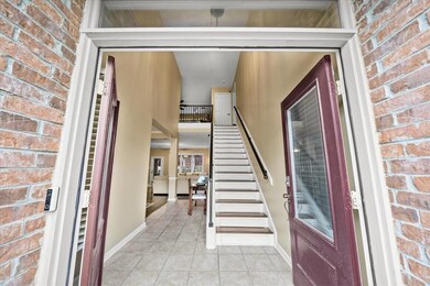 Foyer with light tile patterned floors, stairs, br