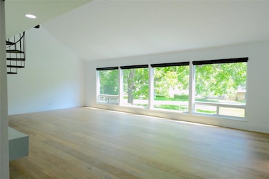 Empty room with wood-type flooring, vaulted ceili
