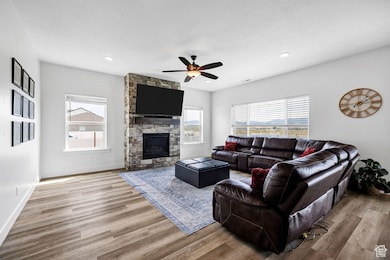 Living room featuring wood finished floors, plenty of natural light, a ceiling fan, a fireplace, and recessed lighting