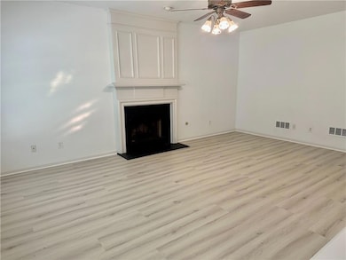 Unfurnished living room with light wood-type flooring, ceiling fan, and a fireplace