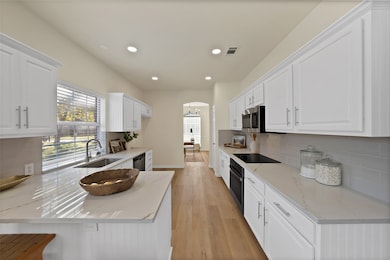 Kitchen featuring decorative backsplash, white cabinets, light wood finished floors, and recessed lighting