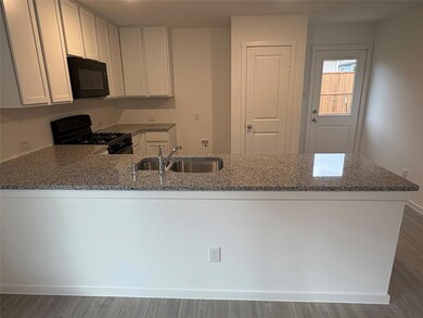 Kitchen with black appliances, white cabinets, sin