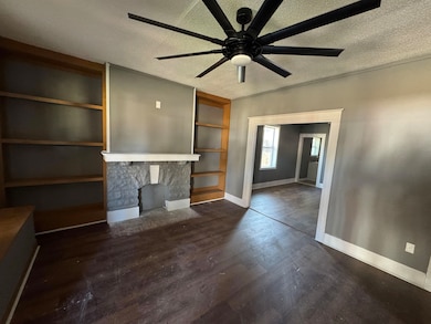 Unfurnished living room featuring ceiling fan, a f