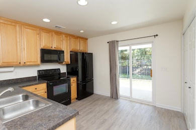 Kitchen featuring black appliances, recessed lighting, dark countertops, light wood-style floors, and light brown cabinets