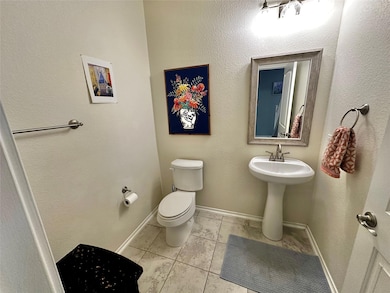 Half bathroom featuring a textured wall and light tile patterned floors