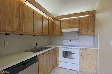 Kitchen with white electric range oven, dishwasher, light countertops, a textured ceiling, and light tile patterned floors