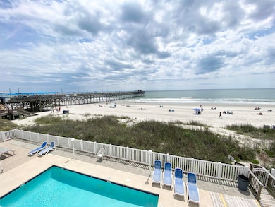 Pool with a patio area, a water view, and a beach 