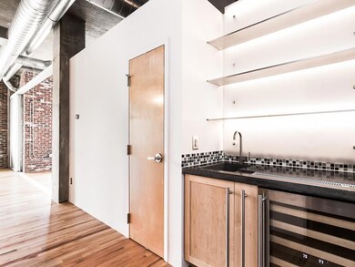 Indoor wet bar featuring wine cooler, light wood-style flooring, backsplash, and brick wall