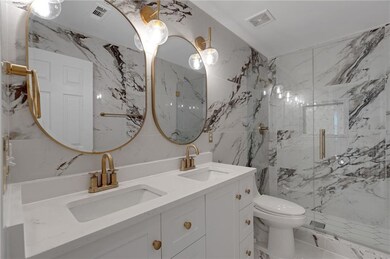 Bathroom featuring toilet, double vanity, a marble