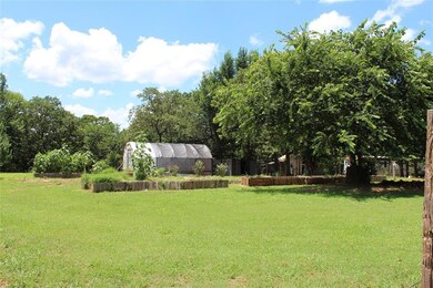 View of grassy yard with a greenhouse and an outbuilding