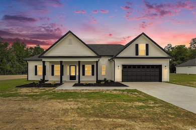 View of front of house with concrete driveway, a yard, a porch, and an attached garage