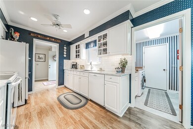 Kitchen with white appliances, backsplash, ceiling fan, light hardwood / wood-style floors, and sink