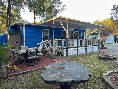 Rear view of property featuring a wooden deck, a patio, a fire pit, and a shed