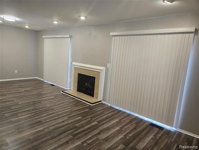 Unfurnished living room with dark wood-type flooring, a fireplace, and recessed lighting
