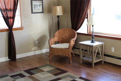 Living area featuring dark wood-style floors, healthy amount of natural light, and baseboard heating