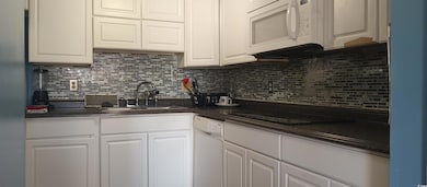 Kitchen with a sink, white appliances, and white cabinetry