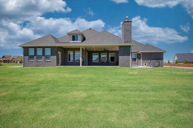 Back of property with a chimney, ceiling fan, brick siding, and roof with shingles