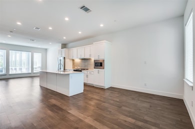 Kitchen with dark wood-style flooring, visible ven