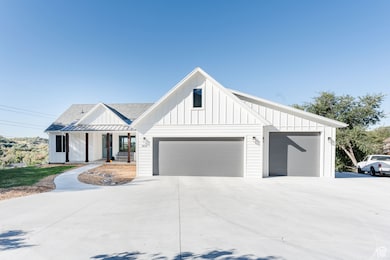 Modern farmhouse style home with board and batten siding, covered porch, roof with shingles, driveway, and an attached garage