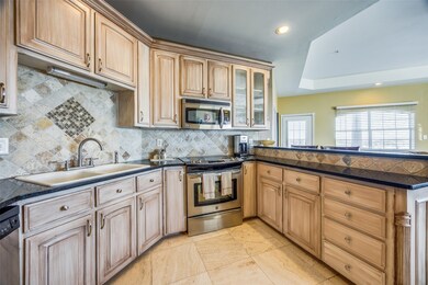 Kitchen with light brown cabinets, stainless steel appliances, decorative backsplash, sink, and kitchen peninsula