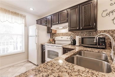 Kitchen with white appliances, light stone counter