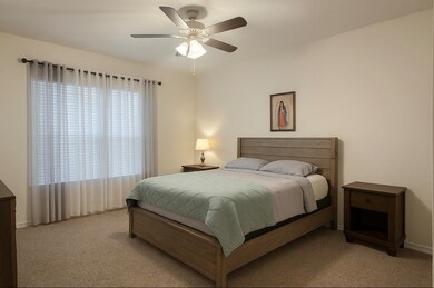 Carpeted bedroom featuring a ceiling fan and baseboards