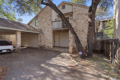 View of front of property featuring a balcony, driveway, an attached carport, and stone siding