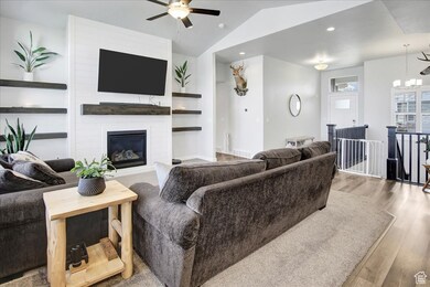 Living area featuring wood finished floors, a fireplace, lofted ceiling, recessed lighting, and a chandelier