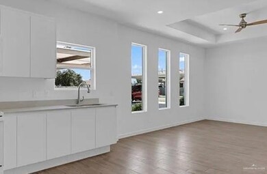 Empty room featuring light wood-type flooring, a raised ceiling, a ceiling fan, and recessed lighting