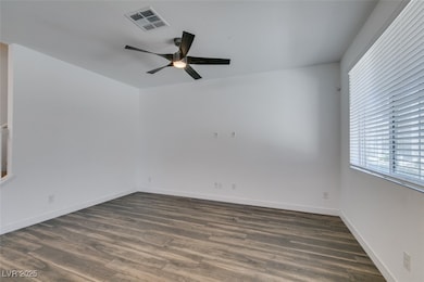 Unfurnished room featuring baseboards, dark wood-style floors, ceiling fan, and visible vents
