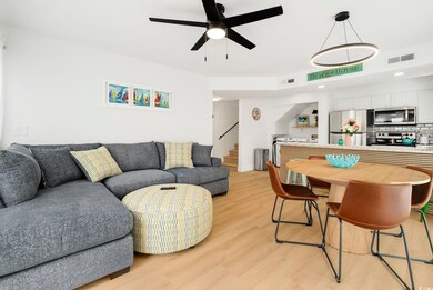 Living room with stairs, light wood-type flooring, and ceiling fan