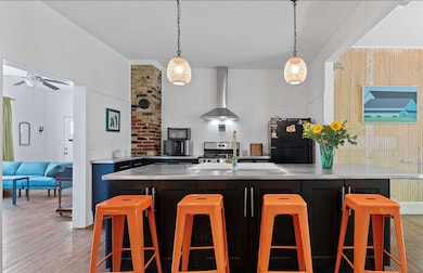 Kitchen with wall chimney exhaust hood, a sink, l