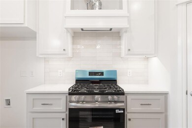 Kitchen featuring stainless steel range with gas stovetop, white cabinetry, and tasteful backsplash
